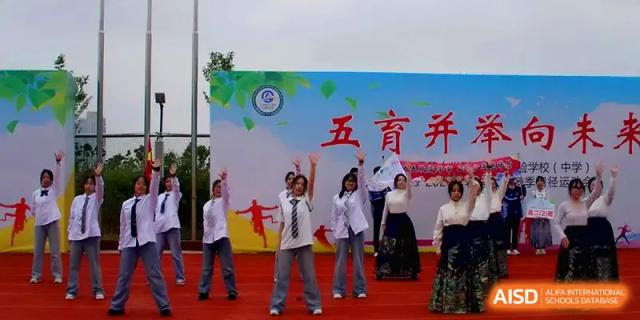 A group of students performs a choreographed dance on a stage with a colorful backdrop at The Guandu Experimental School Affiliated To Shanghai Normal University.