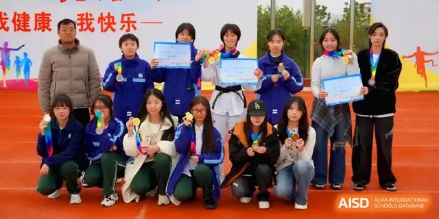 A group of students poses with their awards and certificates on a red track at The Guandu Experimental School Affiliated To Shanghai Normal University.