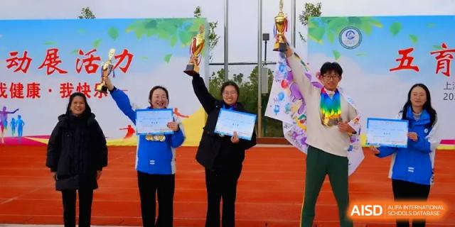 Staff members proudly hold up trophies and certificates during an awards ceremony at The Guandu Experimental School Affiliated To Shanghai Normal University.