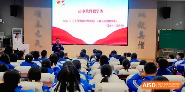 An instructor stands before a seated audience in a lecture hall during an educational seminar at The Middle School Affiliated to Sichuan University.