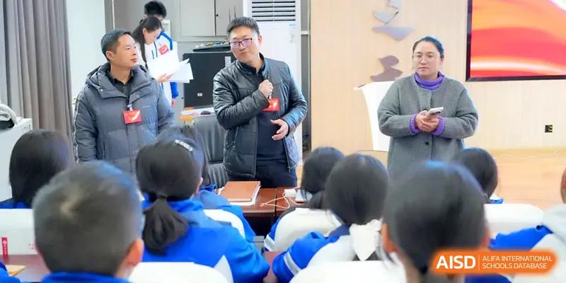A staff member speaks into a microphone while addressing a seated group of students in a hall at The Middle School Affiliated to Sichuan University.