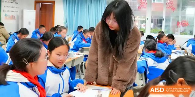 A teacher in a brown coat reviews a student's work during an individual study session in class at The Middle School Affiliated to Sichuan University.