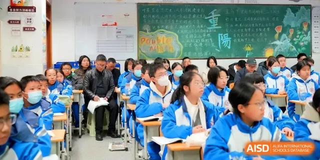 Students sit at their desks in a classroom featuring a large chalkboard with colorful handwriting at The Middle School Affiliated to Sichuan University.