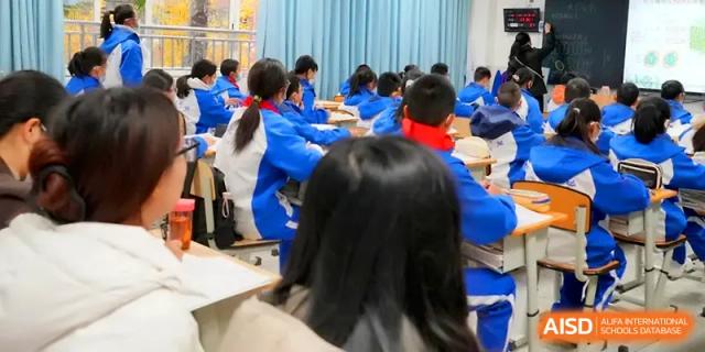 Students in blue and white athletic jackets sit at desks while listening to a classroom lecture at The Middle School Affiliated to Sichuan University.
