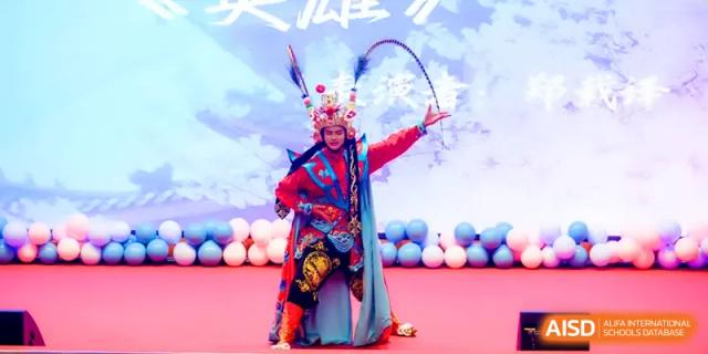 A performer in elaborate traditional costume and headgear performs a dramatic role on stage during a talent showcase at The Middle School Affiliated to Sichuan University.