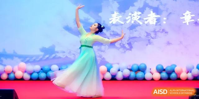 A dancer in a flowing green and white dress performs an elegant routine on a stage during a school cultural event at The Middle School Affiliated to Sichuan University.