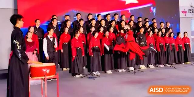 A large choir of students in black and red formal outfits performs a musical piece together on stage at The Middle School Affiliated to Sichuan University.