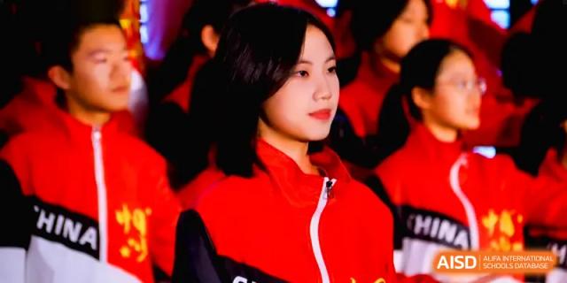 A female student in a red and black jacket looks thoughtfully off-camera during a school event or activity at The Middle School Affiliated to Sichuan University.