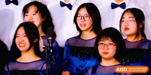 Students in dark formal dresses smile while performing as part of a musical ensemble during a school concert at The Middle School Affiliated to Sichuan University.