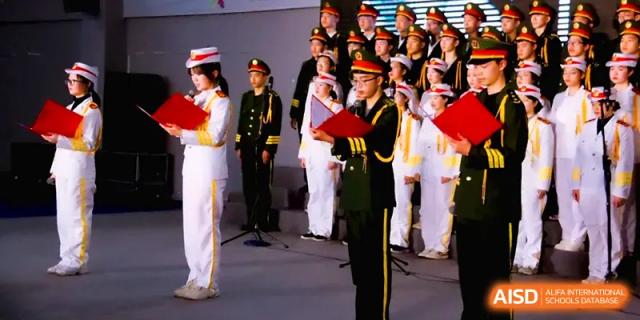 Students in formal military-style uniforms stand on stage during a formal school ceremony or national event at The Middle School Affiliated to Sichuan University.