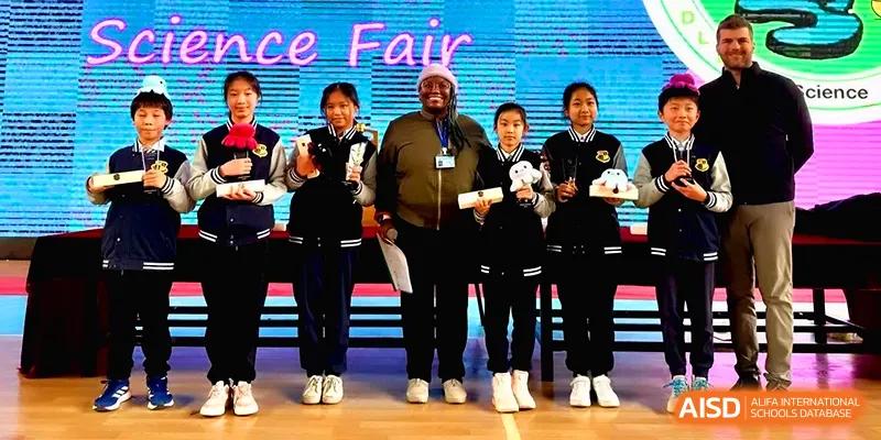 Students stand on stage with a teacher during an awards ceremony at a school science fair at Xiwai International School.