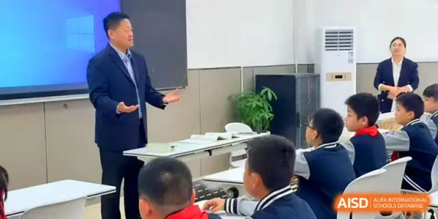 A teacher leads a discussion with a group of students in a modern classroom setting at Xiwai International School.