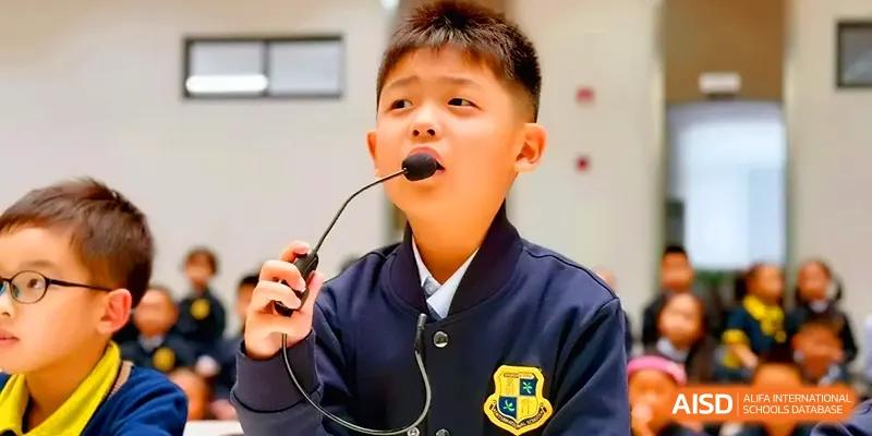 A young student speaks confidently into a desktop microphone during a presentation at Xiwai International School.