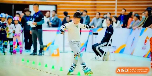 A young boy skillfully navigates an indoor obstacle course on roller skates during a physical education event at Xiwai International School.