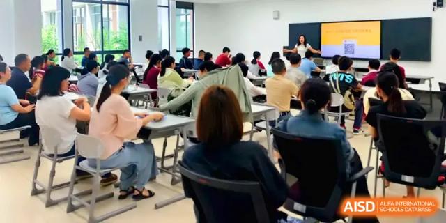 Students participate in a collaborative workshop session, seated in rows while looking toward a presenter at Xuzhou No.1 Middle School.