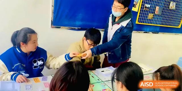 A teacher assists a student with a tabletop project or game during an interactive classroom activity at Xuzhou No.1 Middle School.