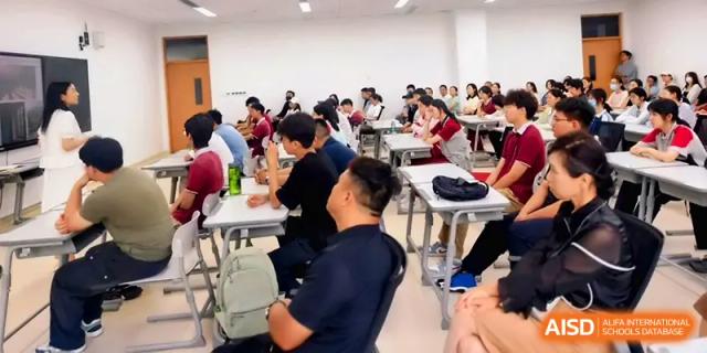 A large group of students sits at their desks, focusing on a lecture in a bright, modern classroom at Xuzhou No.1 Middle School.