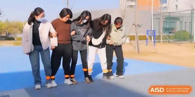 Four students participate in a fun outdoor three-legged race during a sports event at Xuzhou No.1 Middle School.