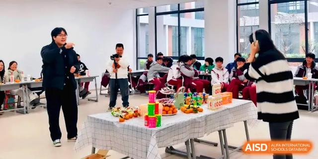 A student films a classroom celebration featuring a table full of snacks and decorations at Xuzhou No.1 Middle School.