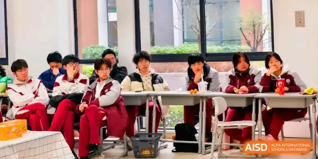 Students sit at their desks and enjoy drinks while watching a performance during a class party at Xuzhou No.1 Middle School.