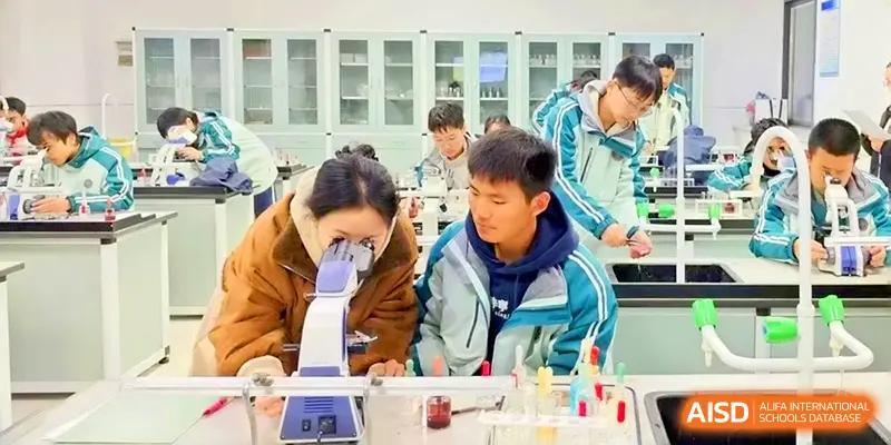 Two students collaborate while using a microscope to examine slides during a biology lesson at Yangzhou High School of Jiangsu Province.