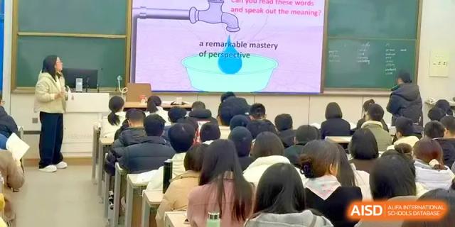 An audience of students looks toward a large screen displaying an illustrated English lesson at Yangzhou High School of Jiangsu Province.
