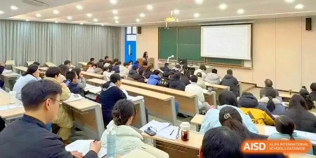 Rows of students sit at long wooden desks in a large classroom, focusing on a teacher's lecture at Yangzhou High School of Jiangsu Province.