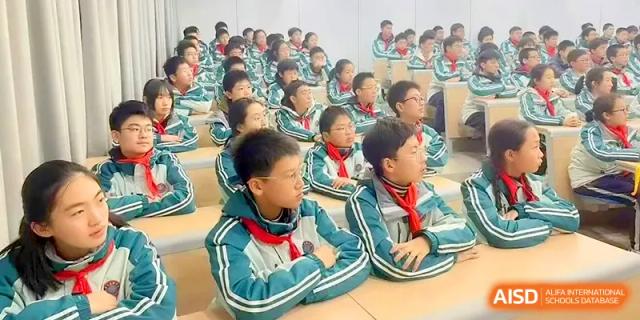 A group of students in teal uniforms sits attentively during a presentation in a lecture hall at Yangzhou High School of Jiangsu Province.