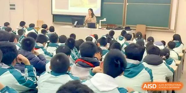 A teacher leads a lesson from a podium for a large classroom of students in uniform at Yangzhou High School of Jiangsu Province.