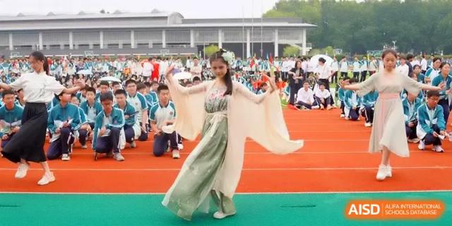 A student in a traditional green and white flowing dress performs a dance on a red track at Yangzhou High School of Jiangsu Province.