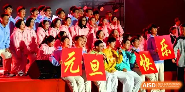 A large student choir in vibrant yellow and pink outfits performs on stage at Yangzhou High School of Jiangsu Province.
