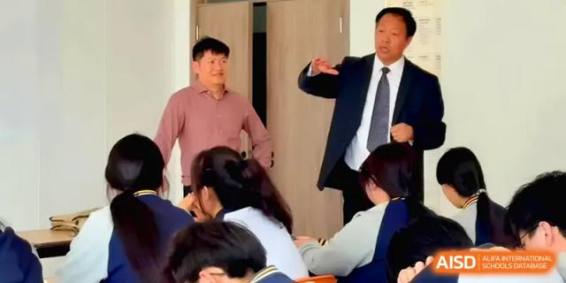 Two faculty members facilitate an interactive learning session, gesturing to emphasize key points to their students at Beijing Xinxuedao Linchuan School.