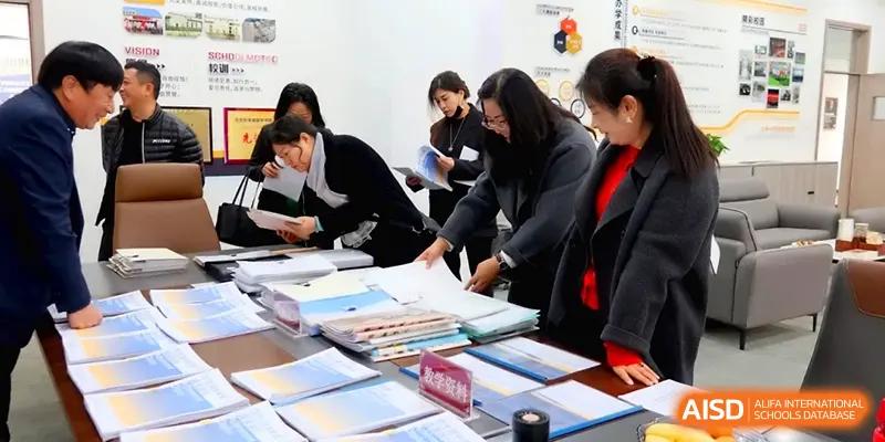 Staff members and teachers gather around a table to review and organize student workbooks and records at Beijing Xinxuedao Linchuan School.