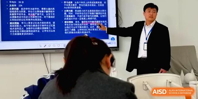 An educator points to a digital screen containing educational text during an interactive lesson for students at Beijing Xinxuedao Linchuan School.