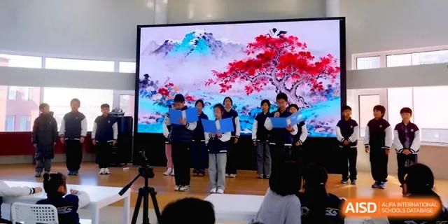 A group of students performs on a stage in front of a large, colorful digital backdrop during a school show at Beijing Xinxuedao Linchuan School.