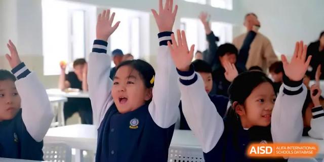 An excited student raises both hands high in the air to answer a question during an interactive lesson at Beijing Xinxuedao Linchuan School.