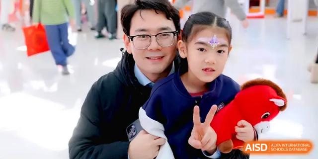 A happy father poses for a photo with his young daughter during a family-oriented school festival at Beijing Xinxuedao Linchuan School.