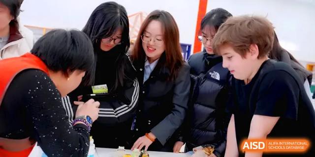 A group of students huddle together to look at a creative project during a collaborative workshop at Beijing Xinxuedao Linchuan School.