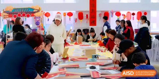 Students and teachers work together at long tables on traditional arts and crafts projects at Beijing Xinxuedao Linchuan School.