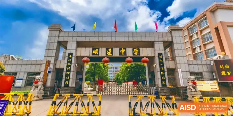 The grand entrance gate of the campus features traditional architecture and colorful flags under a bright blue sky at Changsha Mingda Middle School.