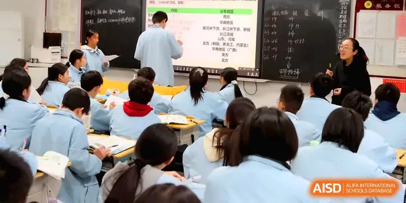 Students focus on a digital presentation while an instructor points to key information on the screen during class at Changsha Mingda Middle School.