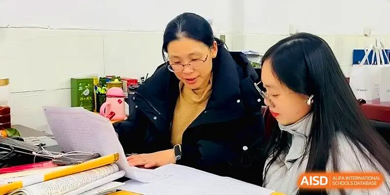 An instructor provides personalized academic guidance to a student by reviewing their notes and assignments at Changsha Mingda Middle School.