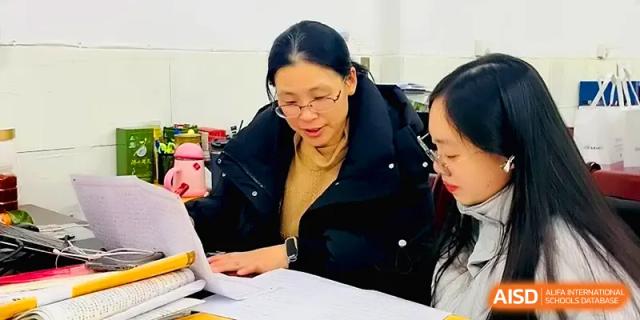 An instructor provides personalized academic guidance to a student by reviewing their notes and assignments at Changsha Mingda Middle School.