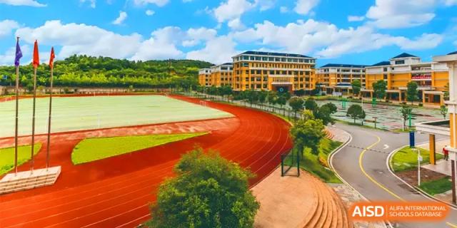 A stunning aerial view shows the red running track and modern campus buildings surrounded by lush greenery at Changsha Mingda Middle School.
