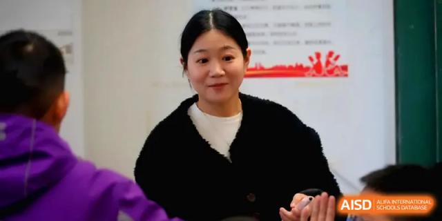 A female staff member smiles warmly during an indoor meeting, representing the dedicated faculty at Changsha Mingda Middle School.