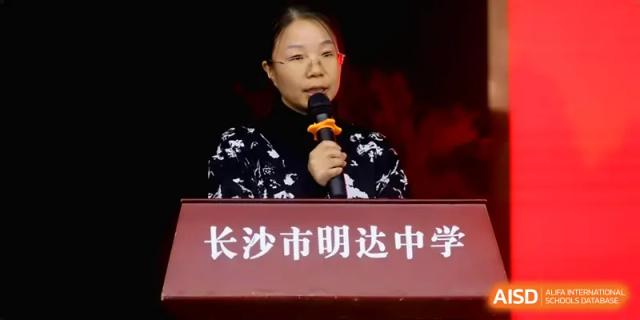 A student representative speaks confidently into a microphone at a podium during a formal school ceremony at Changsha Mingda Middle School.