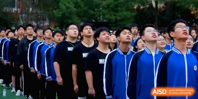 Male students in black team shirts look upward with focus during a competitive outdoor sports event at Changsha Mingda Middle School.