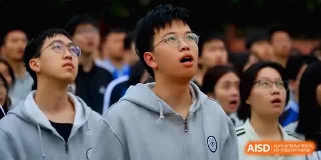 A student with glasses looks on with an expression of concentration during an outdoor school activity at Changsha Mingda Middle School.