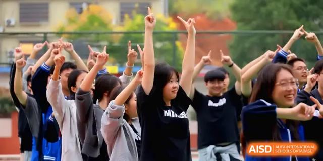 Students cheer enthusiastically with their hands raised during a spirited team competition on campus at Changsha Mingda Middle School.