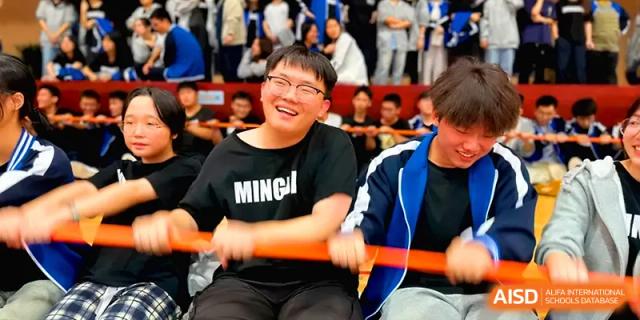 A student laughs joyfully while participating in a high-energy group competition with his classmates at Changsha Mingda Middle School.
